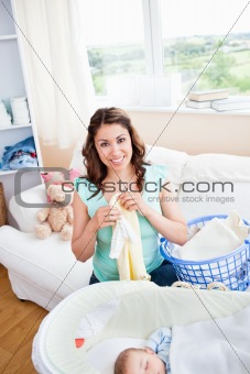 Cheerful young mother doing the laundry while her baby is sleepi