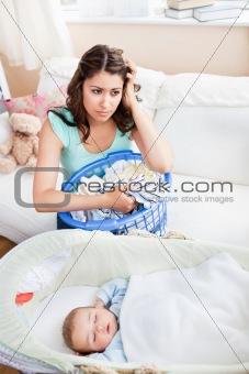 Tired young mother doing the laundry while her baby is sleeping 