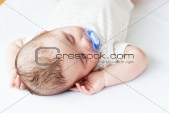 Portrait of an adorable baby with a pacifier sleeping in a bed