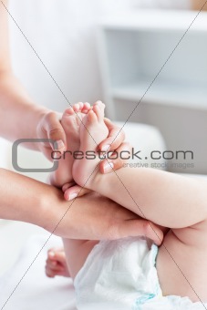 Caring young mother changing the diaper of her baby