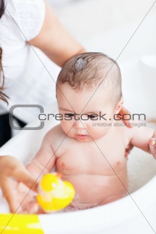 Adorable baby taking a bath wihile his adorable mother takes car