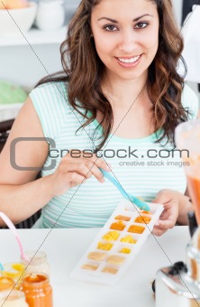 Portrait of a bright young mother preparing food for her baby in the kitchen