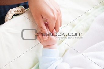 Close-up of a young mother holding her baby's hand