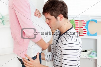 Portrait of a kind man kissing his pregnant wife's belly