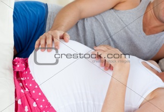Close-up of a young pregnant woman lying on bed with her husband
