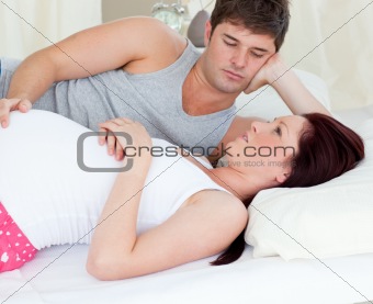 Worried pregnant woman lying on bed with her husband