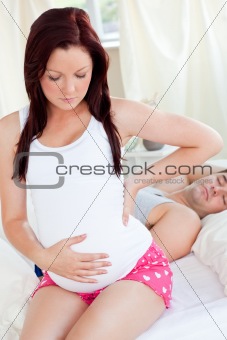 Portrait of a beautiful pregnant woman sitting on bed