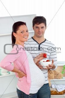 Portrait of a smiling pregnant woman eating strawberries and of 