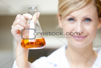 Close-up of a female scientist holding an erlenmeyer and smiling
