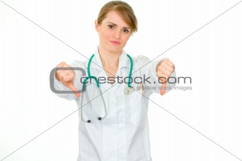 Displeased medical doctor woman showing thumbs down gesture
