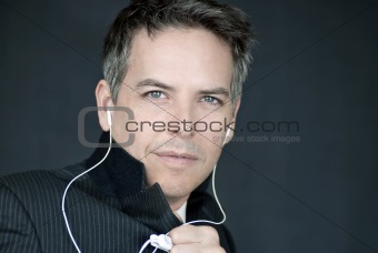 Confident Businessman Wearing Headphones Holds Jacket Closed