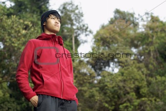 Asian in sweater standing outdoors looking far away