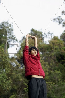 Happy asian man stretching arms outdoors 