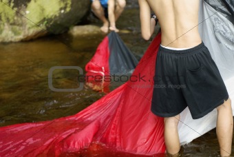 People washing tent in river
Two asian men washing red tent in flowing river water