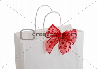Closeup of white paper gift bag with red bow
