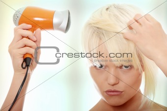 Blonde woman using hair drier 