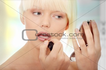 A beautiful young woman applying her make-up