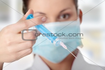 Young nurse in mask with syringe