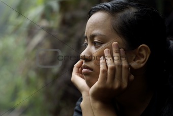 Troubled asian teen girl thinking with hands on face