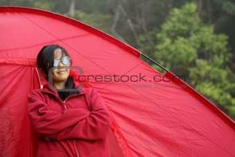 Asian malay teen girl standing beside red tent outdoors