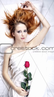 Fashion red-haired girl with rose in the bedroom.