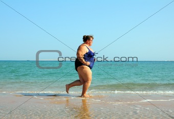 overweight woman running on beach