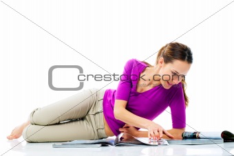 woman lying on the floor reading a magazine on white background studio