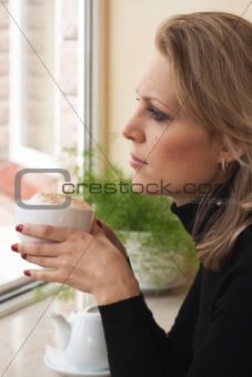 Portrait of a young blonde beauty with a cup of cappuccino