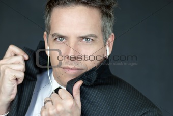 Confident Businessman Wearing Headphones Looks To Camera As He A