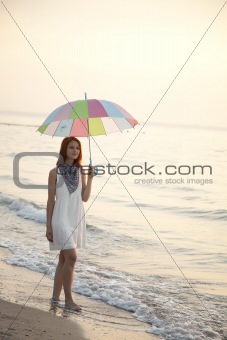 Young beautiful girl on the beach at sunrise with umbrella.