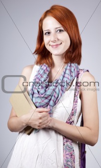Red-haired girl keep book in hand. Studio shot.