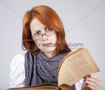 Young doubting fashion girl in glasses with old book