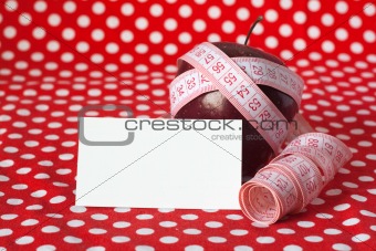 Red apple and measuring tape on a red background and card