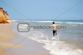 Boy running by beach 