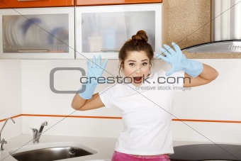 Young woman in blue rubber gloves in the kitchen