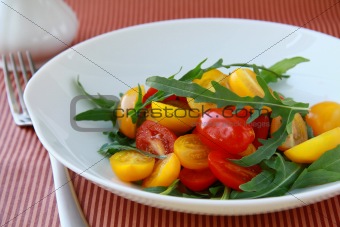 salad with arugula and cherry tomatoes on a striped background