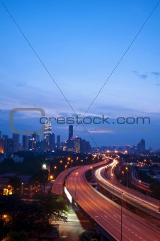 Light trail at busy highway with the view of kuala lumpur city