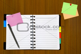 open notepad and colored memo with pen on wood background