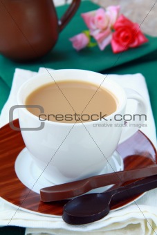 tea with milk in a white cup on a green tablecloth