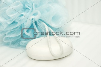 Blue shower puff and soap on tiles