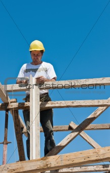 Construction worker on scaffold busy on formwork preparation
