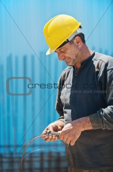 Construction worker cutting wire with pair of pliers
