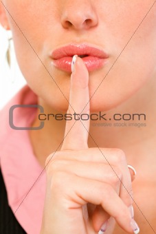 Closeup of business woman with finger at mouth. Shh gesture
