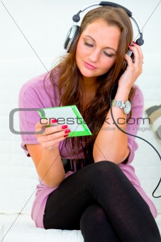 Attractive woman sitting on couch and listening music in headphones
