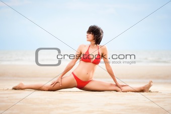 Beautiful woman doing yoga exercise on the beach