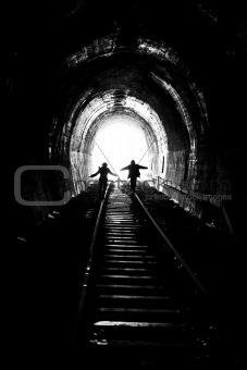 man and woman going towards the light, on railway tracks