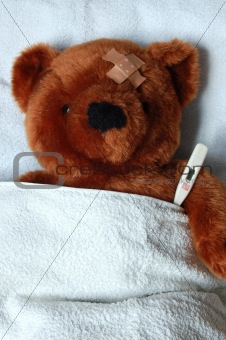 sick teddy with injury in bed