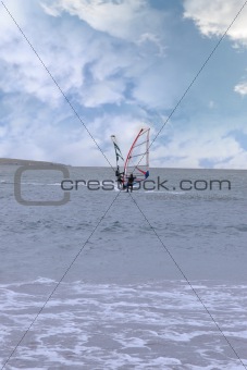 two surfers windsurfing in a storm