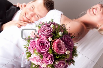 young couple in wedding wear with bouquet of roses