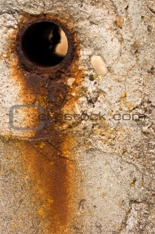 Rusty hole in concrete wall